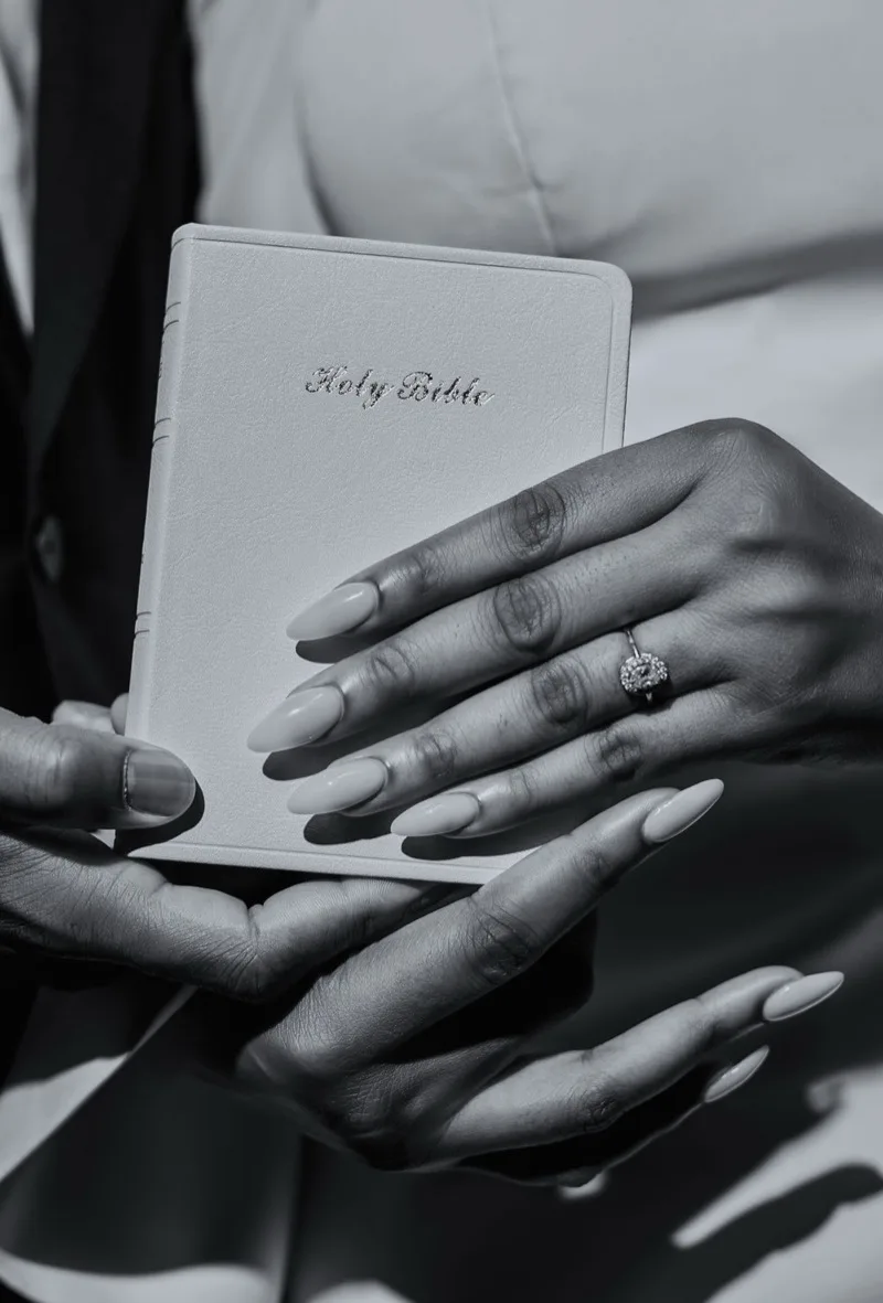 Hands on the Bible with the engagement ring